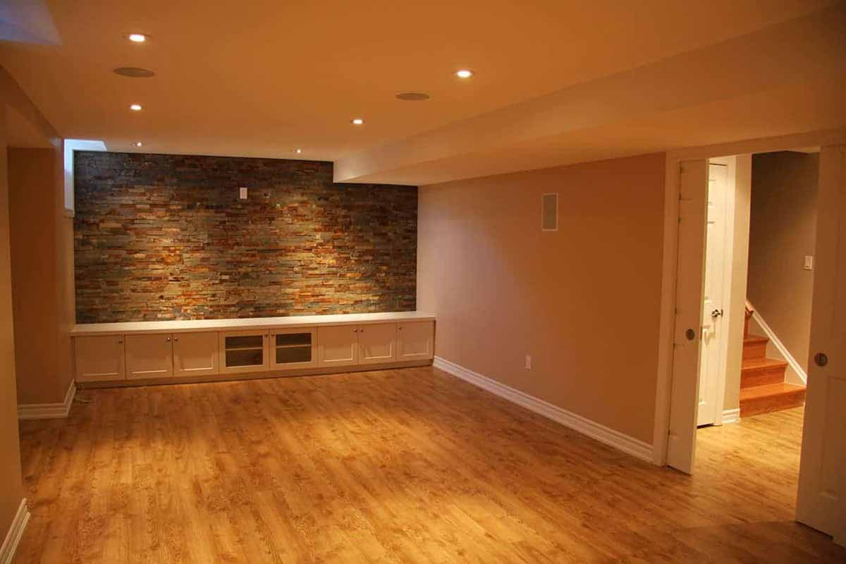 Refinished basement with custom cabinetry, brick facade and lighting
